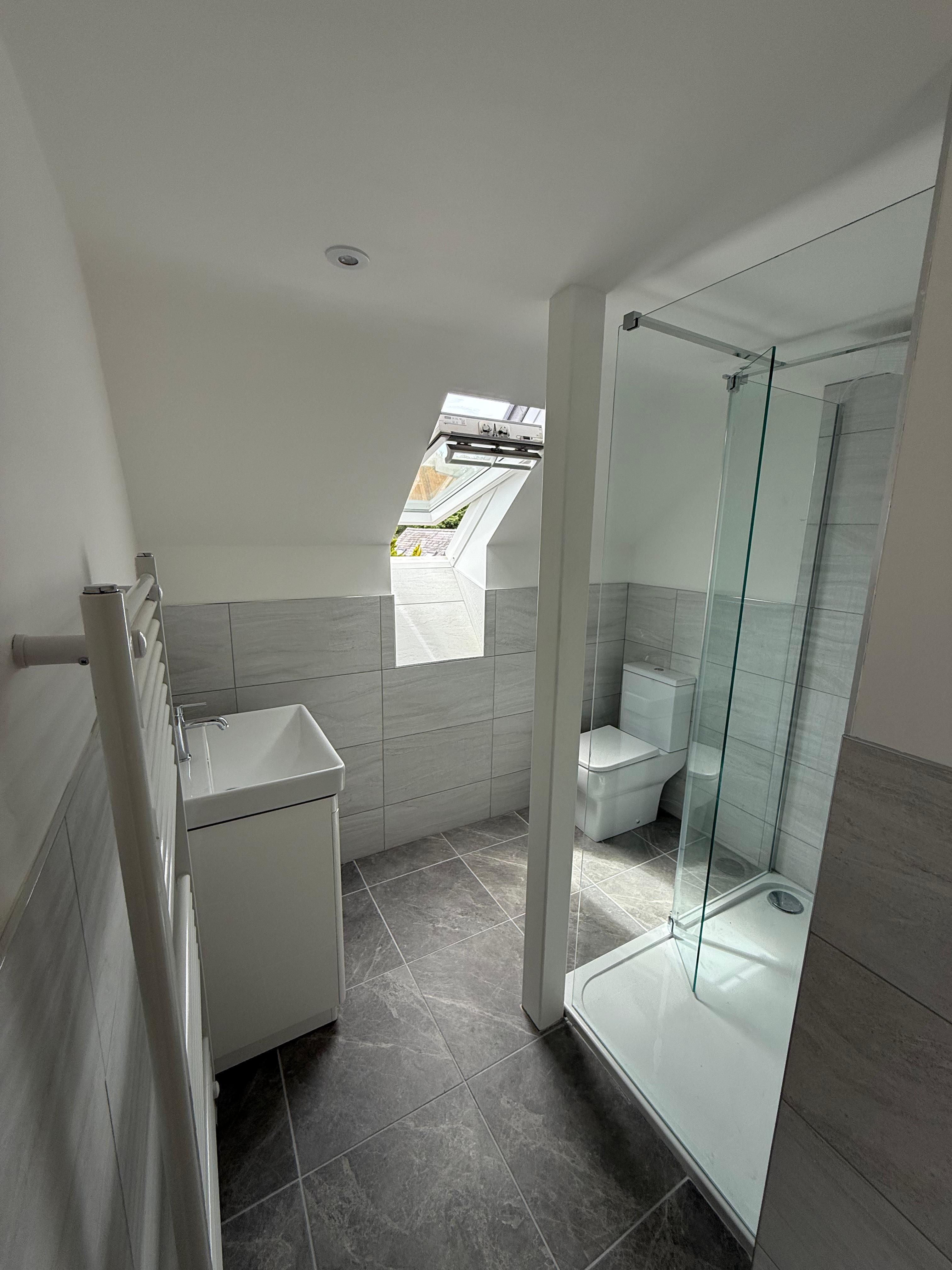 Loft shower room with a corner enclosure, skylight and grey stone-effect tiles