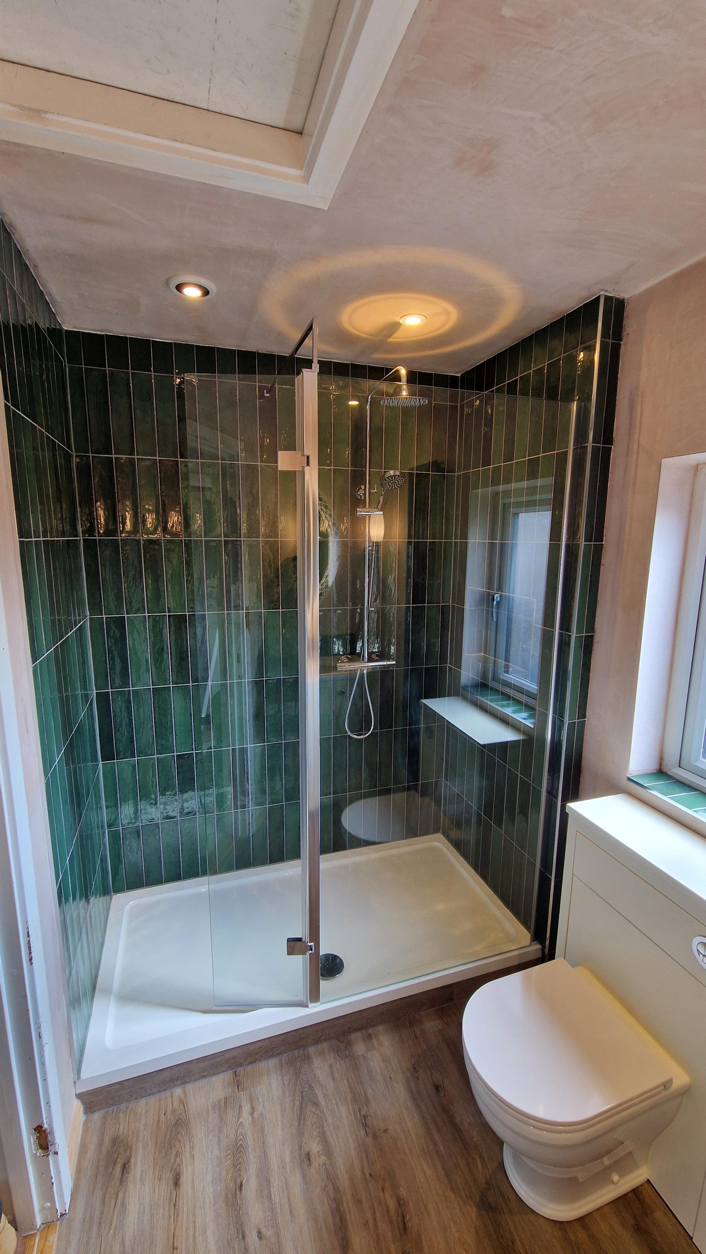 Shower enclosure with green gloss wall tiles and a wood-effect floor