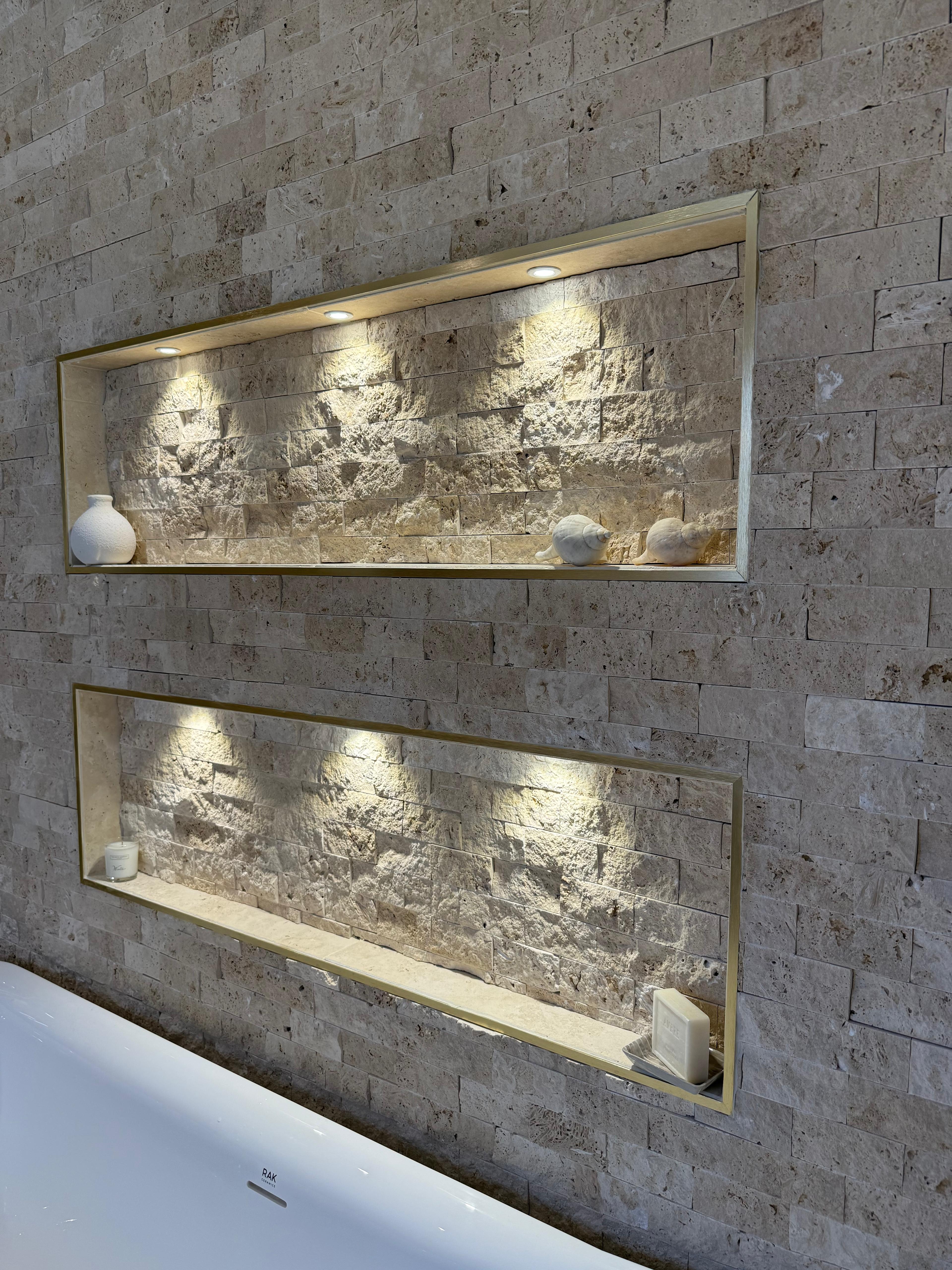 Split-face stone wall tiling with two recessed, lit alcoves